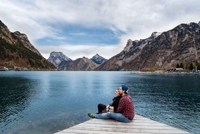 Couple sitting on a dock by a lake with mountains