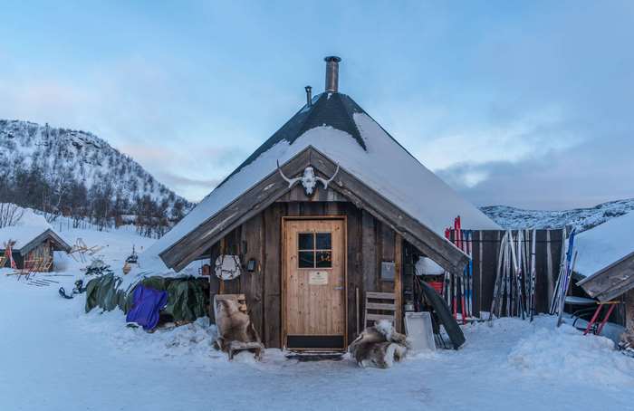 Wooden cabin in snowy landscape with skis