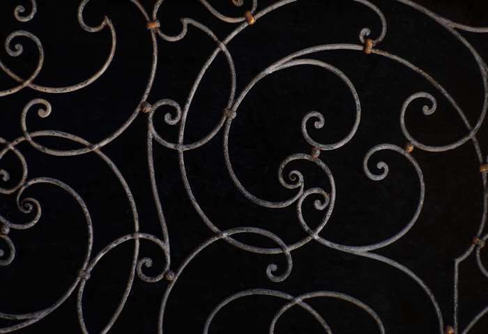 Ornate wrought iron scrollwork pattern on black background