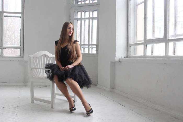 Young woman in a black dress sitting on a chair