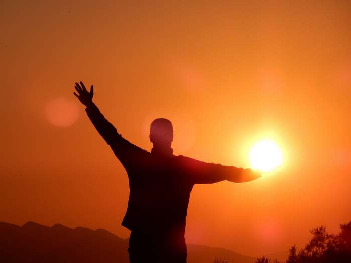 Silhouette of a person with arms outstretched at sunset 4K