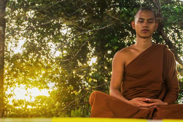 Monk meditating at sunset in a forest