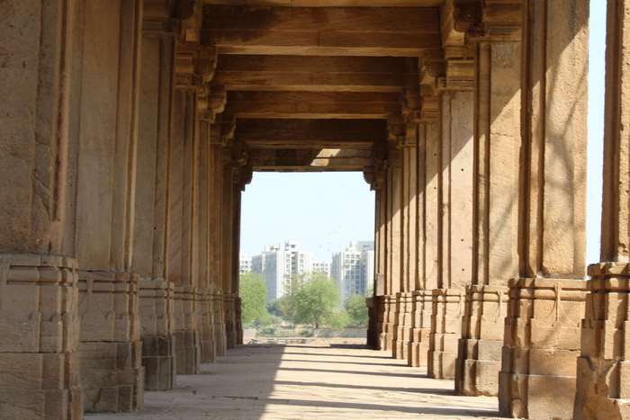 Ancient stone colonnade with modern city skyline in background