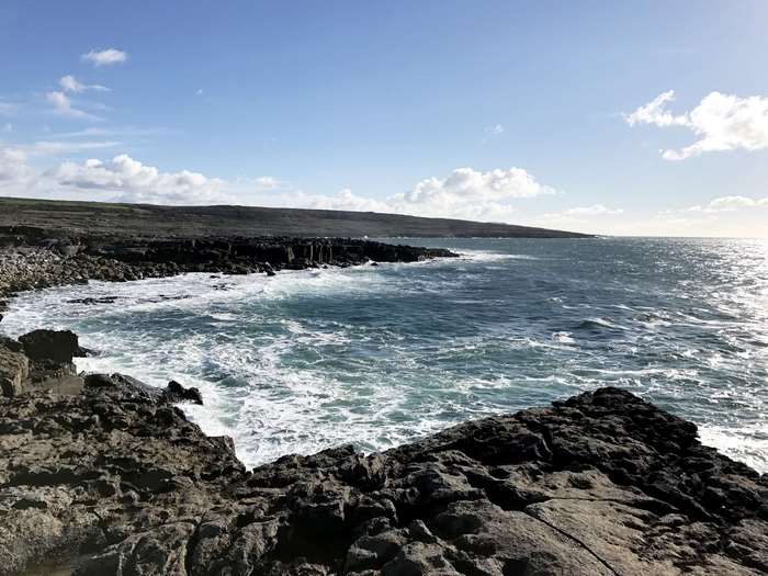 Rocky coast with waves crashing under a blue sky
