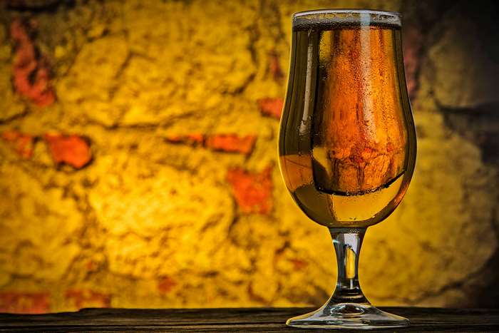 Glass of beer with condensation against a stone wall