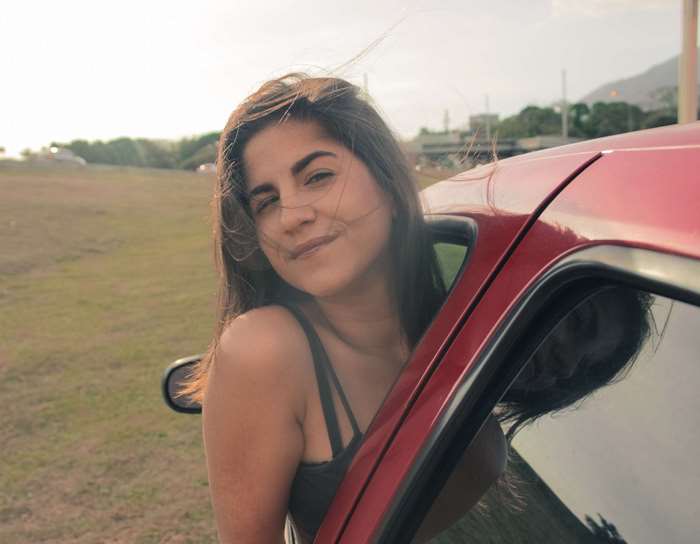 Young woman leaning out of a red car