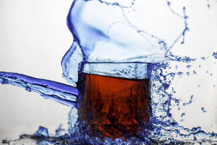 Blue liquid splashing out of a glass with red liquid