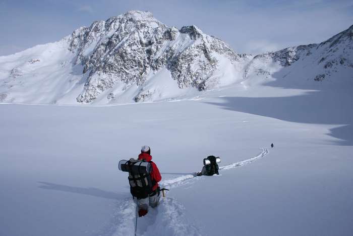 Two hikers trekking across a snowy mountain landscape