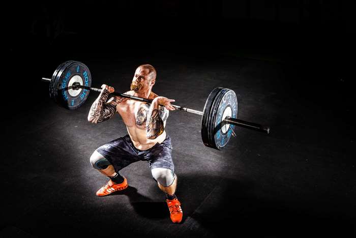 Man performing a barbell squat in a gym