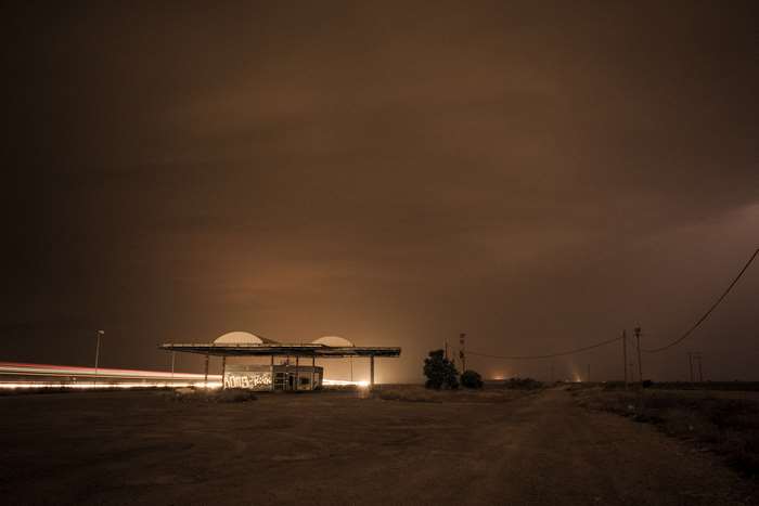 Abandoned gas station at night with light trails