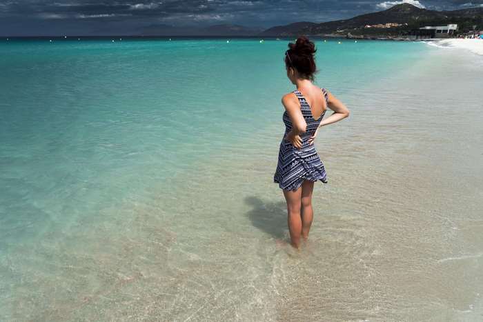 Woman in dress standing in the ocean at a beach