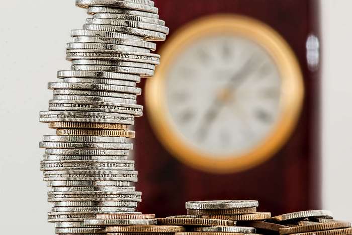 Stacked Coins and Clock Representing Time and Wealth