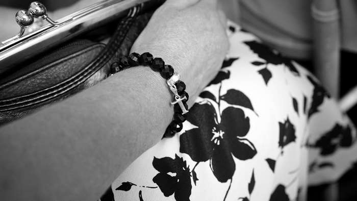Woman wearing a black beaded bracelet with a cross charm
