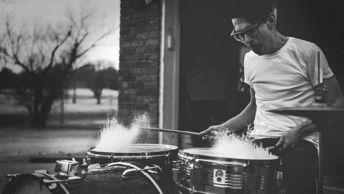 Man playing drums with water splashing