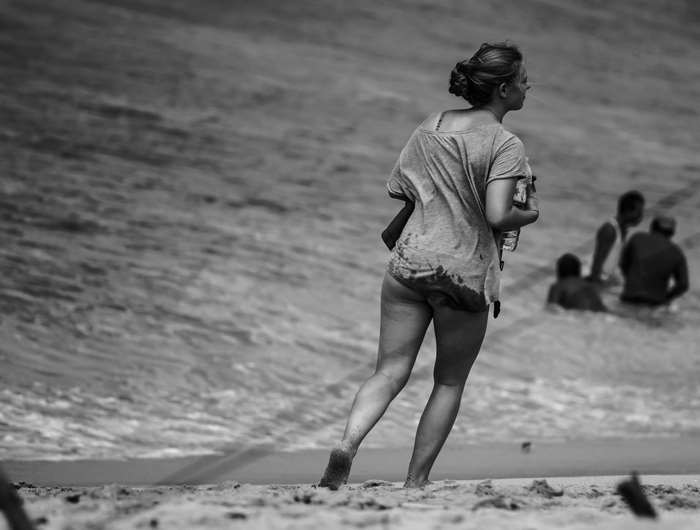 Woman walking on beach with people in water