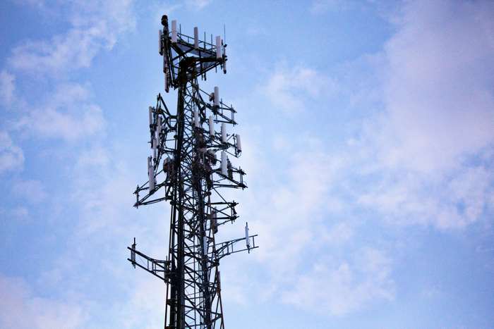 Cell tower with antennas against a cloudy sky