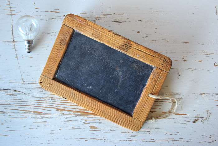 Empty wooden framed blackboard and light bulb on a table
