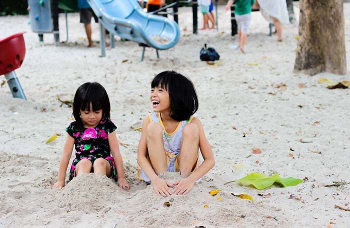 Two young girls playing in the sand at a playground
