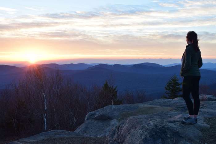 Woman hiking on mountain top at sunset