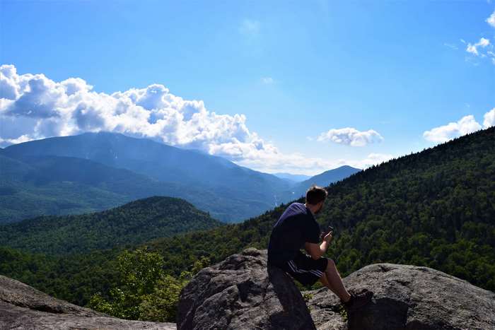 Man on mountain top with scenic mountain range background
