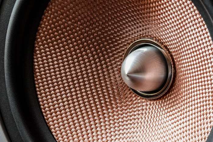 Close-up of a modern speaker with a metallic dome and woven cone