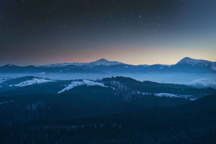 Snowy mountains under a starry night sky