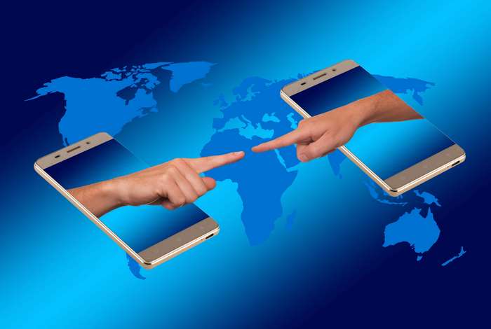 Hands reaching from smartphones across world map