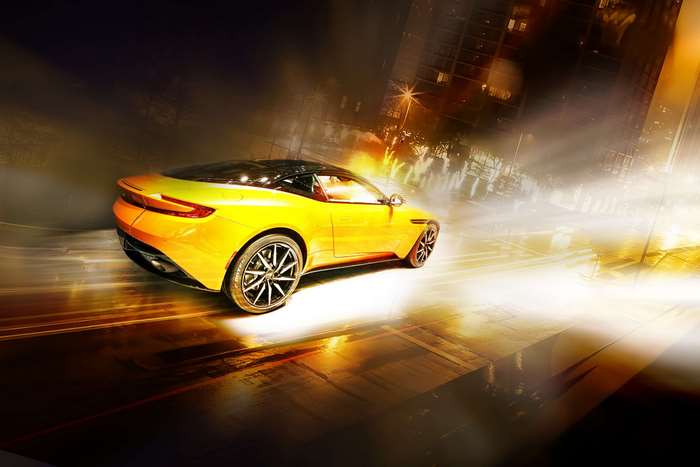 Yellow Aston Martin sports car on a city street at night