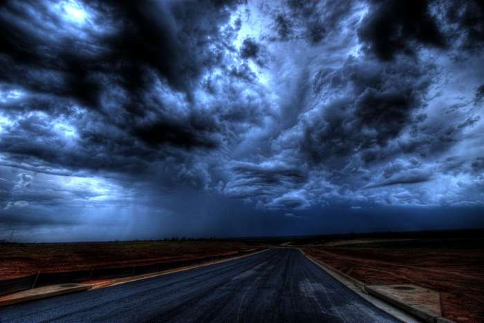 Dark storm clouds over a road at twilight