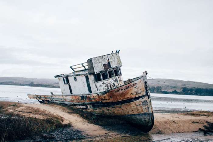 Wrecked boat named Point Reyes on a muddy shore
