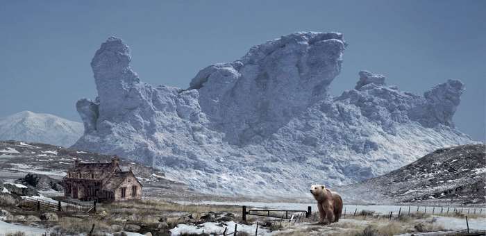 Bear in a snowy landscape with a house and mountains