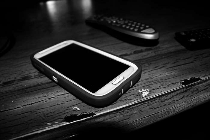 Samsung phone and remotes on wooden table