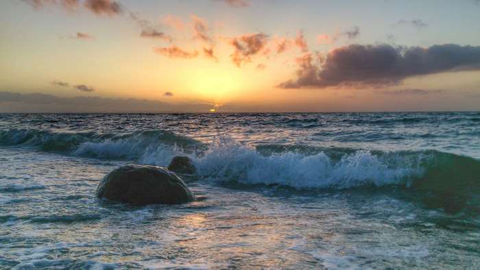 Sunset over the Baltic Sea with waves and rocks