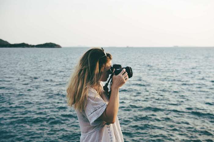 Woman taking photos by the sea