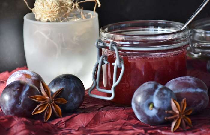 Plum jam in a jar with fresh plums and star anise