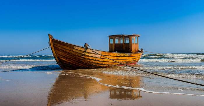 Wooden fishing boat on a sandy beach with waves