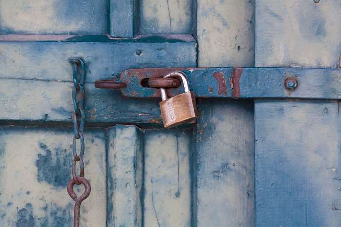 Rusty padlock on a blue wooden door with chain
