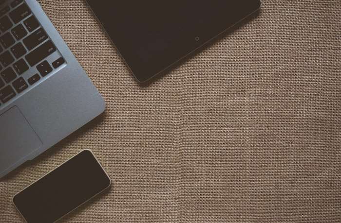 Apple laptop, tablet, and smartphone on sackcloth texture