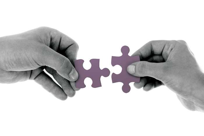 Hands Connecting Purple Puzzle Pieces