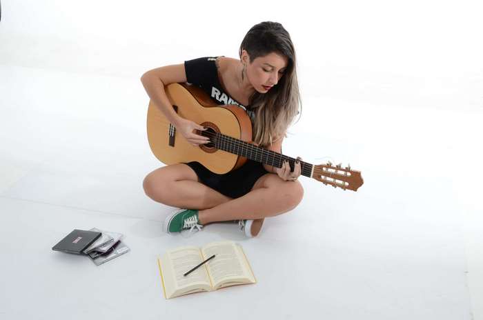 Woman playing acoustic guitar with book and CDs