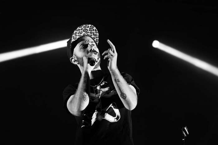 Man with beard singing into microphone on stage