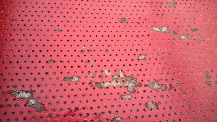 Red perforated metal with rust and wear 4K