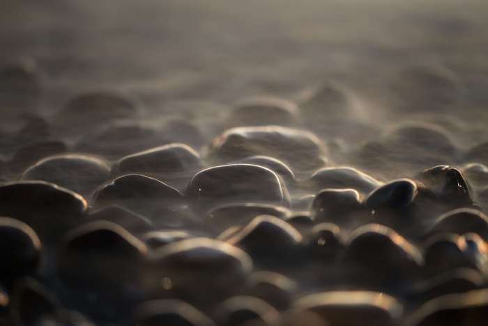 Close-up of wet stones with mist at sunset