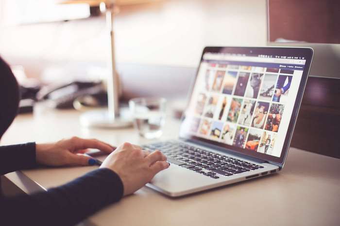 Person typing on a laptop displaying a photo collage