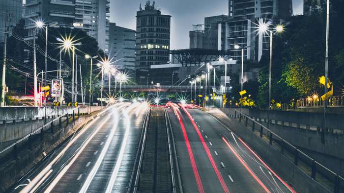 Time lapse of traffic on a highway at dusk with city buildings