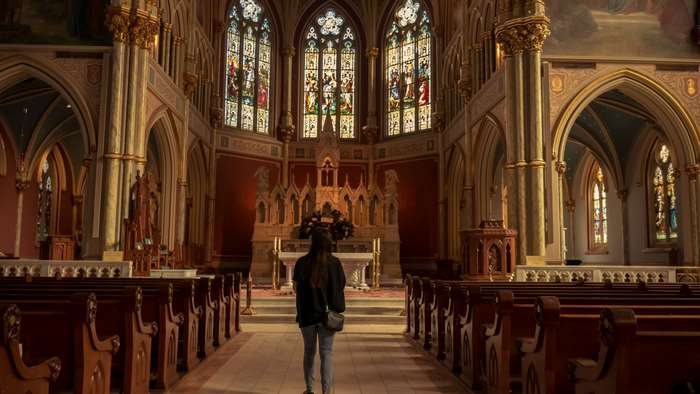 Person walking down church aisle towards altar with stained glass