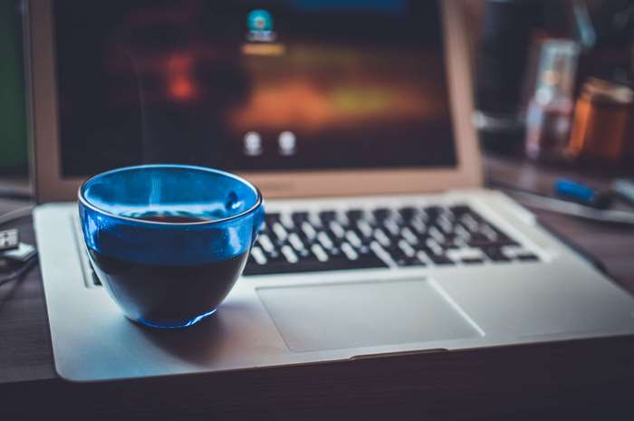 Blue cup of coffee on a laptop