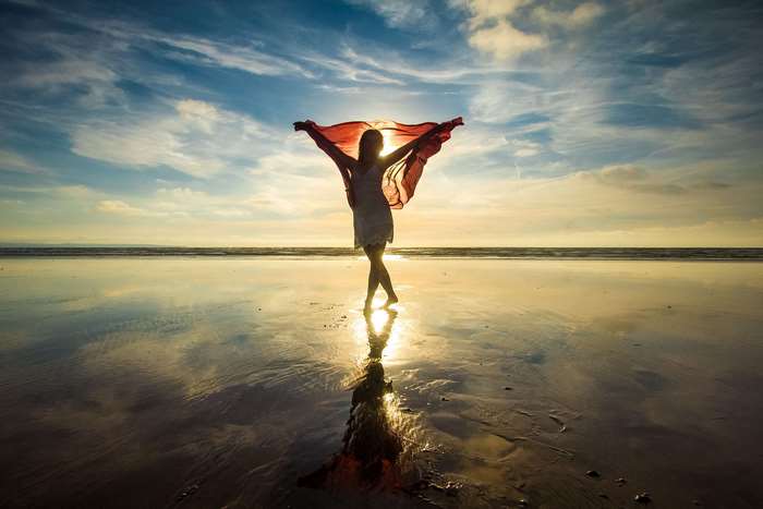 Woman with scarf on beach at sunset 4K