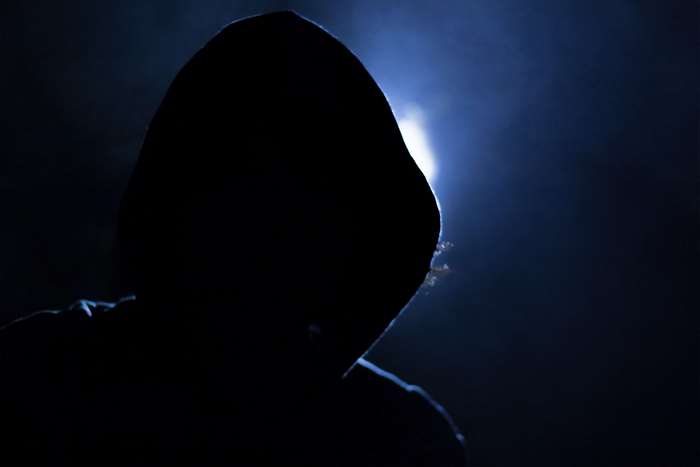 Silhouette of a person in a hood with blue light