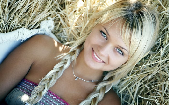 Blonde girl with pigtails lying in hay